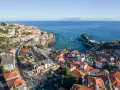 Widok na miasteczko Camara de Lobos z licznymi łodziami w zatoce. Domy z czerwonymi dachami schodzą ku morzu.