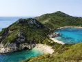 Malownicza zatoka z piaszczystą plażą na Korfu, otoczona zielonymi wzgórzami i krystalicznie czystą wodą.