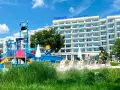 Kolorowy aquapark i hotel Maritim Paradise Blue Albena w Bułgarii, z leżakami i zieloną trawą.