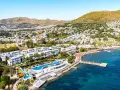 Malownicze wybrzeże Turcji Egejskiej z białymi hotelami, basenami i plażą pełną leżaków.