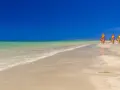 Piękna, słoneczna plaża w Tunezji we wrześniu. Trzy kolorowe żagle desek do windsurfingu stoją na piasku.