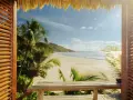 Widok z drewnianej werandy na piaszczystą plażę, palmy i turkusowe morze. Idealna wyspa na wakacje.