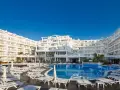 Idealna pogoda na Costa Brava: hotel z basenem i leżakami pod błękitnym niebem.
