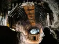 W ciemnym tunelu kopalni, gdzie drewniane wsporniki tworzą łuk, widać sylwetkę górnika. Czy to osówka, czy włodarz?