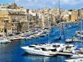 Malta plan zwiedzania: malowniczy port z łodziami i zabytkowymi budynkami w tle.