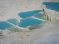 Turkusowe wody tworzą kaskady na białych tarasach wapiennych w Pamukkale w Turcji.