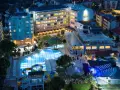 Nocny widok na Meridia Beach Hotel z oświetlonymi basenami, zjeżdżalniami i restauracją.