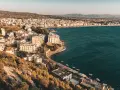 Widok na Loutraki, Grecja, z zabudowaniami wzdłuż wybrzeża i wzgórzami w tle.