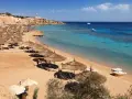 Piękna plaża w Egipcie w lutym. Słoneczna pogoda, turkusowe morze, leżaki i parasole zapraszają do relaksu.