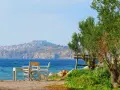 Piękna pogoda na Lesbos. Stół i krzesła czekają na plaży, w tle widać zamek i miasteczko.