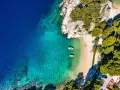 Widok z lotu ptaka na zatokę z krystalicznie czystą wodą, piaszczystą plażą i łodziami. Idealne miejsce na wakacje, jak z pocztówki z Chorwacji.