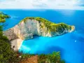 Grecja w kwietniu zachwyca pogodą. Widok na Navagio Beach z klifu, turkusowe morze i biały piasek.