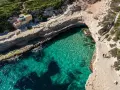 Malta plaza: turkusowa woda w zatoce, skaliste klify i schody prowadzące do ukrytej plaży.