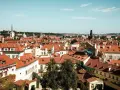 Widok na dachy Pragi, idealne miejsce na city break. W oddali wieże kościołów i wieża zegarowa.