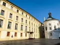 Zamek na Hradczanach, z jego żółtą fasadą i białą, okrągłą kaplicą, prezentuje się majestatycznie pod błękitnym niebem.