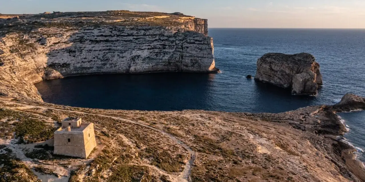 Malta pogoda w styczniu: słoneczny dzień nad zatoką z wieżą strażniczą i skalistymi klifami.