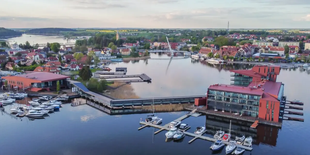 Malownicze Mazury: nowoczesna marina z hotelami i licznymi łodziami, idealne miejsce na relaks i odkrywanie atrakcji regionu.