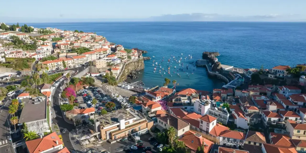 Widok na miasteczko Camara de Lobos z licznymi łodziami w zatoce. Domy z czerwonymi dachami schodzą ku morzu.