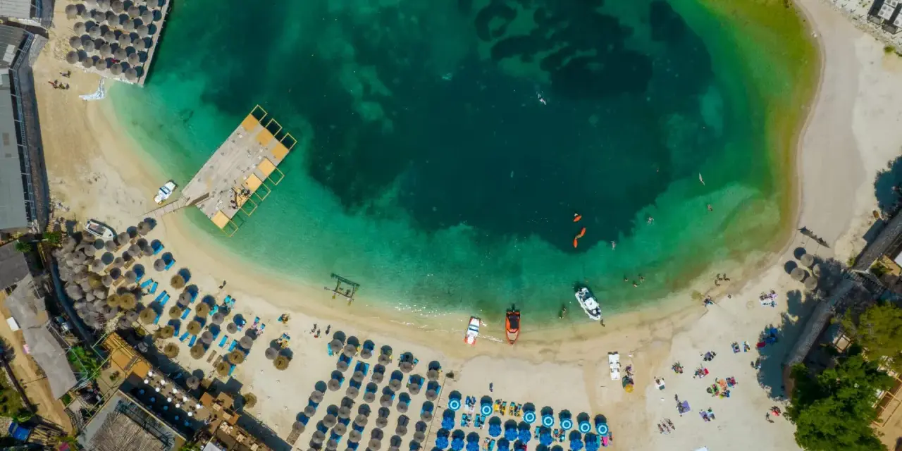Albania, lipiec: słoneczna pogoda na plaży z turkusową wodą, leżakami i parasolami. Idealne warunki do wypoczynku.