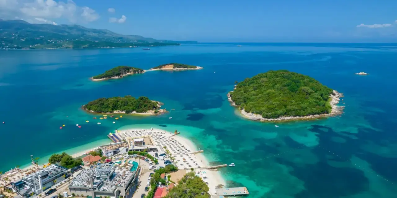 Rajska plaża z wysepkami, idealne albania atrakcje. Woda kusi turkusowym kolorem, a zielone wyspy zapraszają do odkrycia.