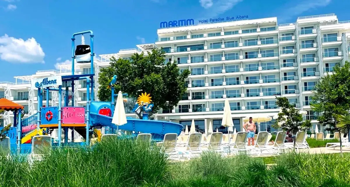 Kolorowy aquapark i hotel Maritim Paradise Blue Albena w Bułgarii, z leżakami i zieloną trawą.