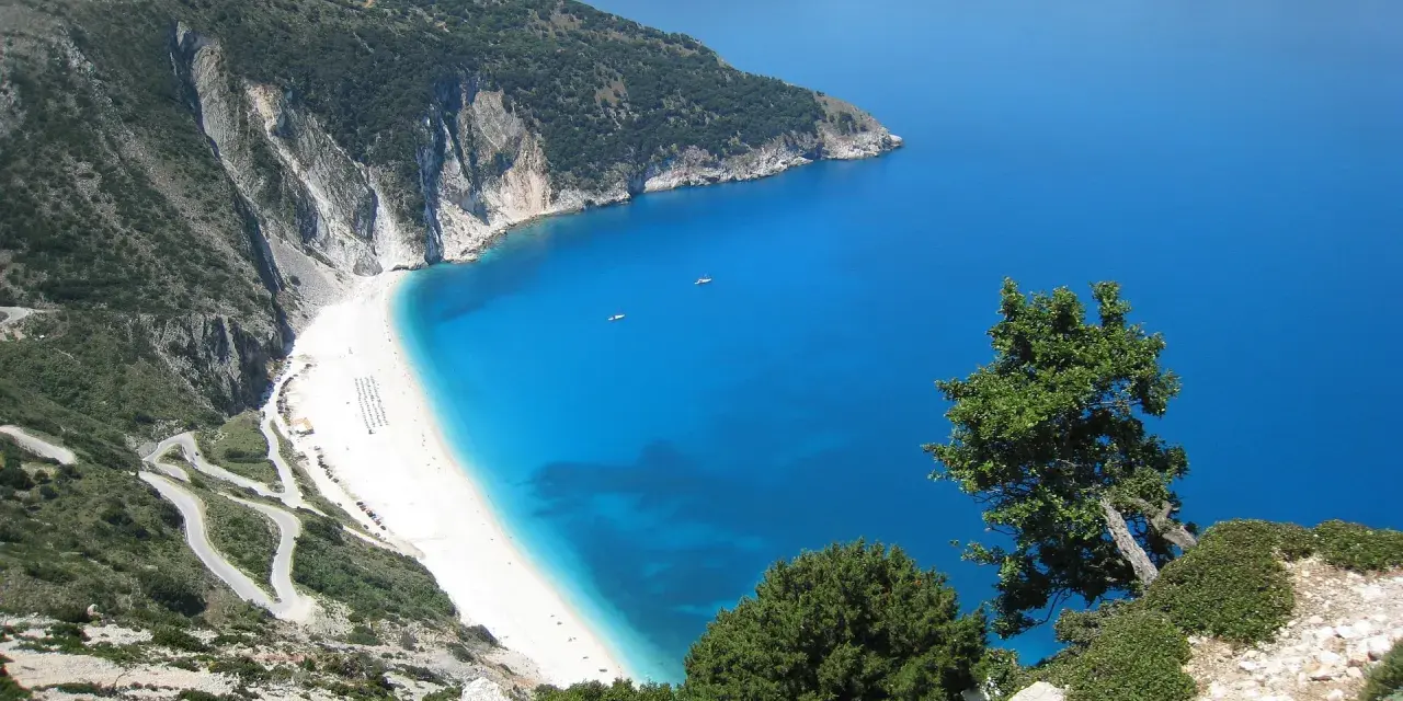 Malownicza plaża Myrtos na Kefalonii, Grecja w październiku. Kręta droga prowadzi do białego piasku i turkusowego morza.