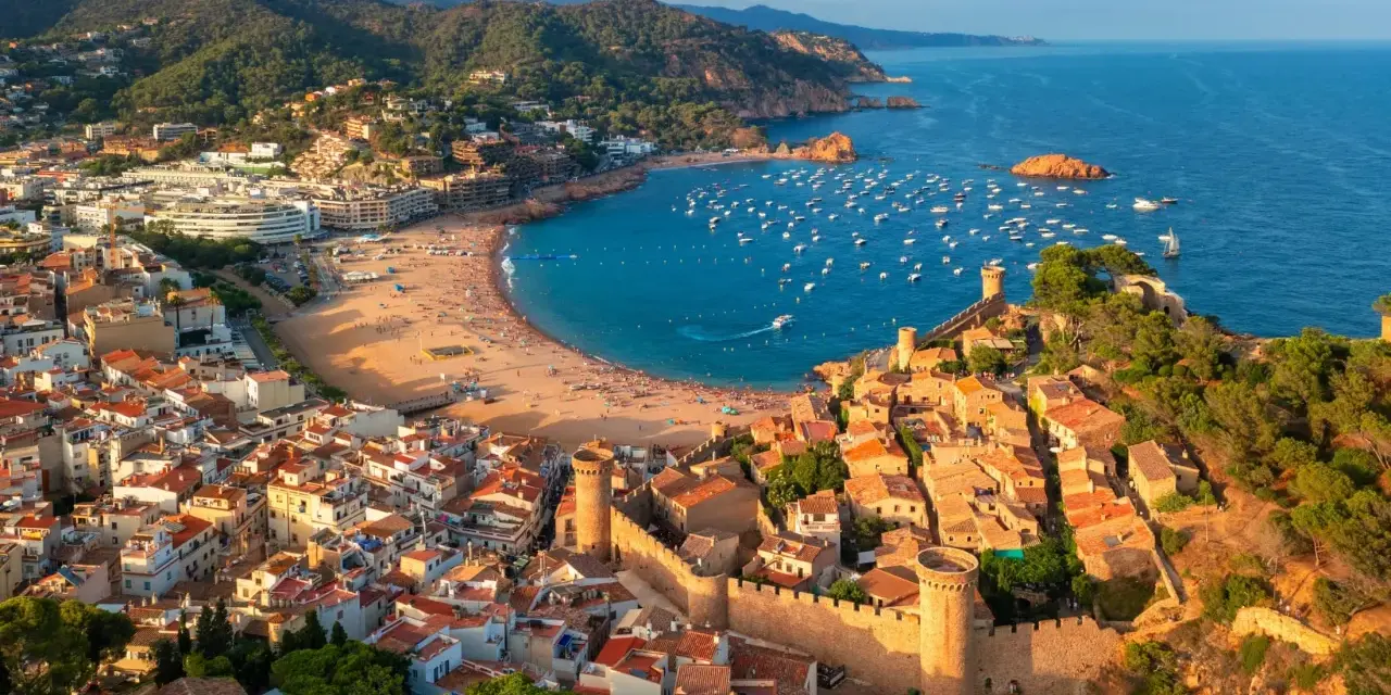 Widok na średniowieczne miasteczko z zamkiem i zatokę pełną łodzi. To idealne miejsce na odkrywanie atrakcji Costa Brava.