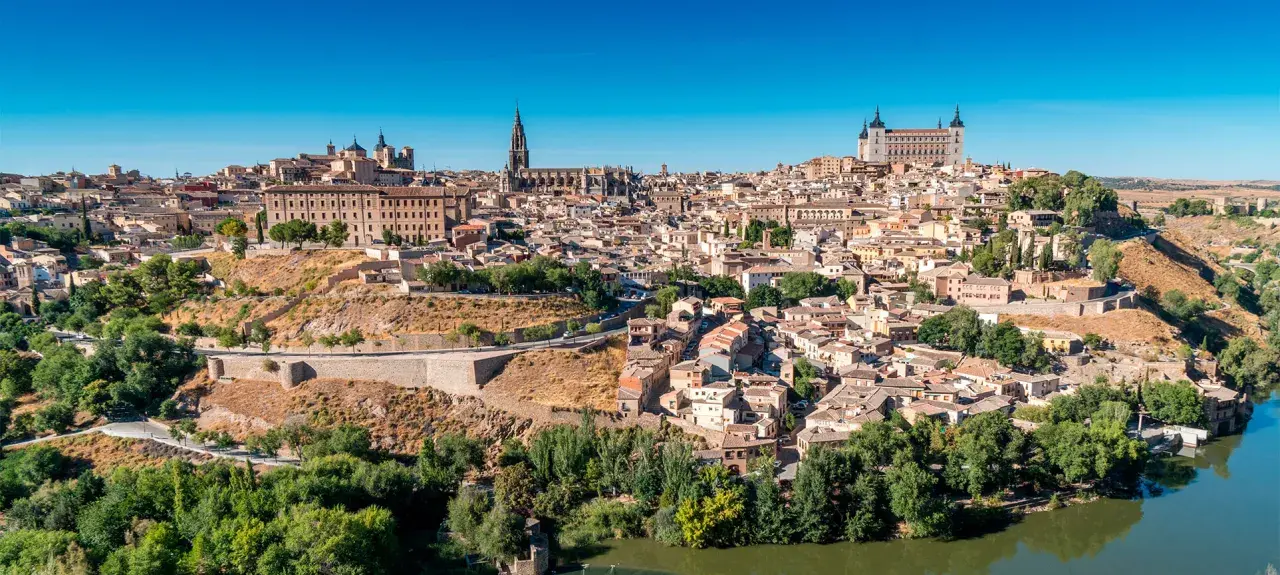 Widok na historyczne miasto Toledo w Hiszpanii, z katedrą i Alcázarem górującymi nad zabudowaniami.