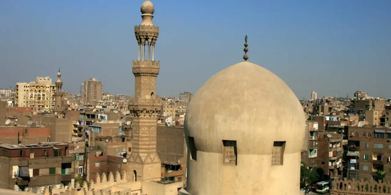 Widok na kopułę i minaret meczetu w Kairze, stolicy Egiptu, na tle miejskiego krajobrazu.