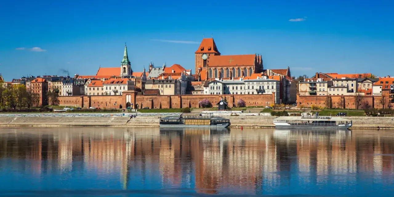 Widok na zabytkowe centrum Torunia z Wisłą w tle. Zobacz, co warto zobaczyć w Toruniu: katedrę, ratusz i średniowieczne mury.