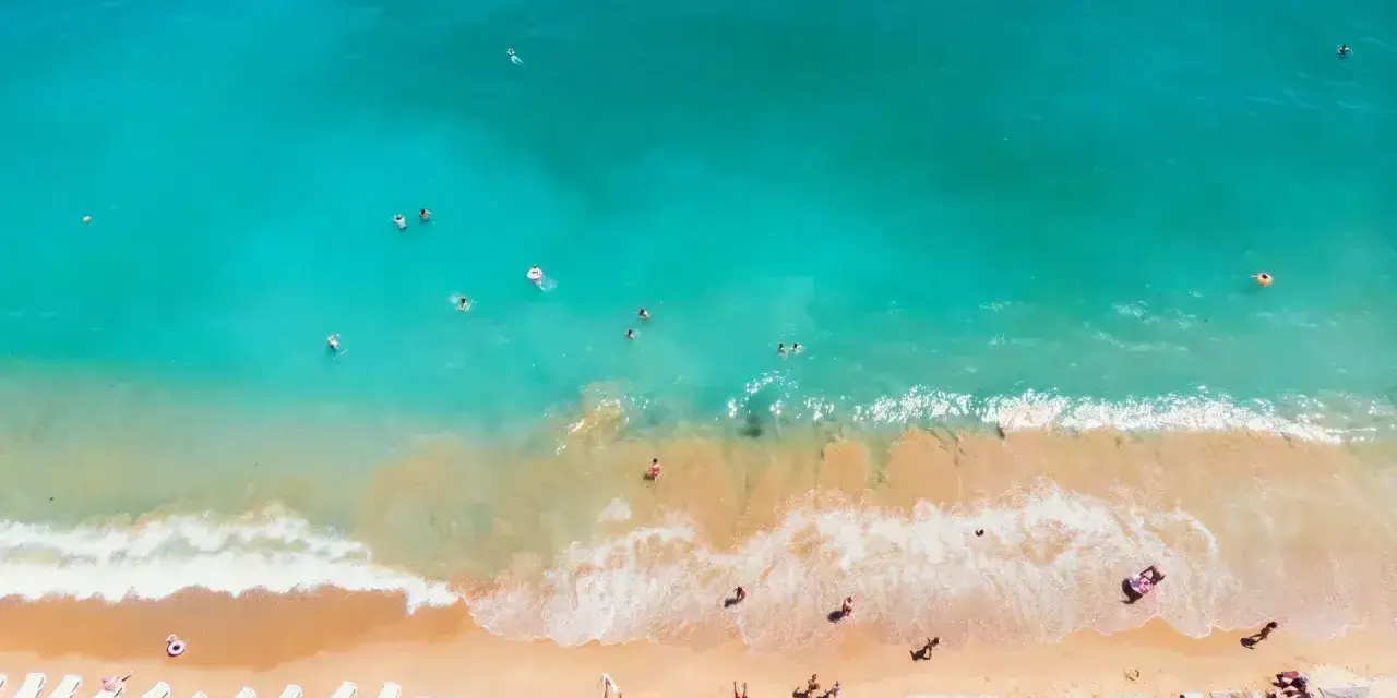 Słoneczna plaża w Bułgarii, turkusowe morze zaprasza do kąpieli. Leżaki i parasole czekają na plażowiczów.