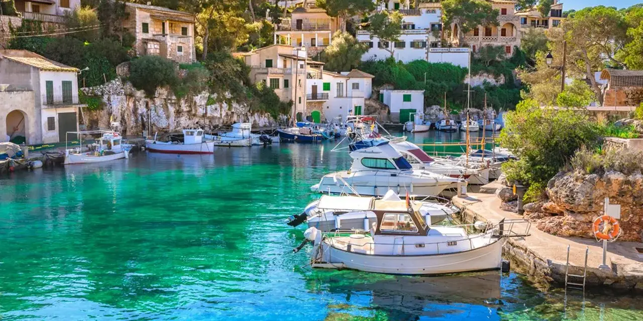Malowniczy port na Balearach, gdzie turkusowa woda otacza zacumowane łodzie. Takie widoki oferują baleary, jakie wyspy zachwycają każdego!