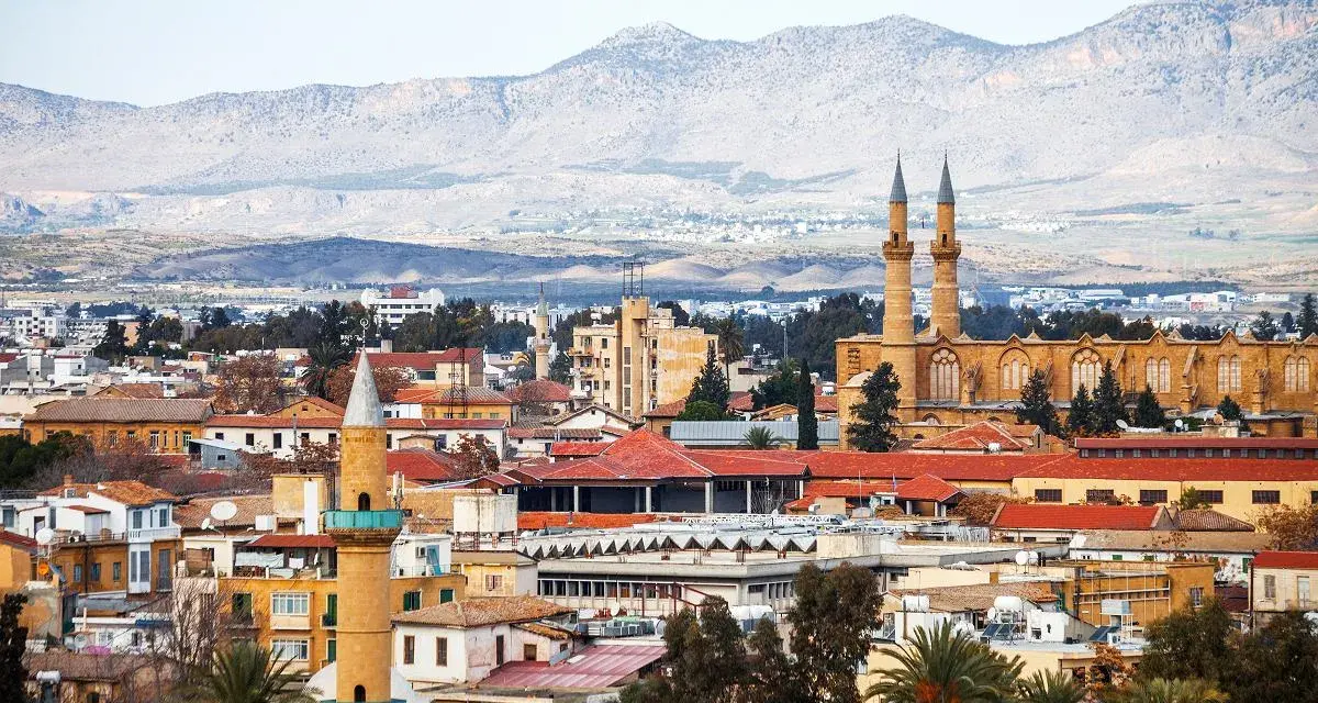 Widok na miasto z minaretami i budynkami o czerwonych dachach, w tle góry. To stolica Cypru, Nikozja.
