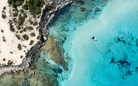 Plaża z turkusową wodą i łodzią, skaliste wybrzeże. Czy to Pafos czy Larnaka?