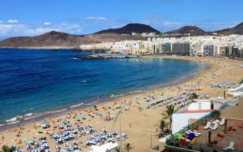 Słoneczna plaża Las Canteras na Gran Canarii, z turystami cieszącymi się ciepłą wodą. Idealna temperatura wody na Gran Canarii zachęca do kąpieli.