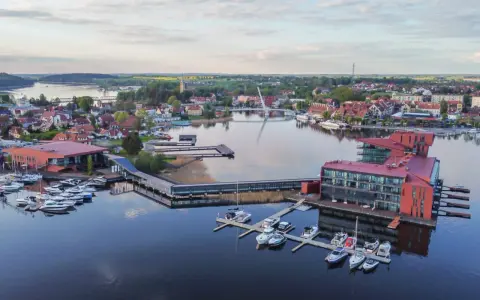 Malownicze Mazury: nowoczesna marina z hotelami i licznymi łodziami, idealne miejsce na relaks i odkrywanie atrakcji regionu.