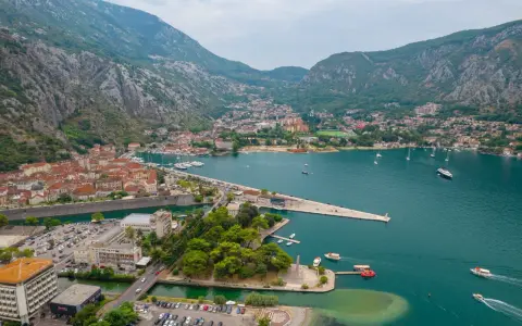 Widok na zatokę z górami w tle, miasto Kotor w Czarnogórze, z łodziami i budynkami.