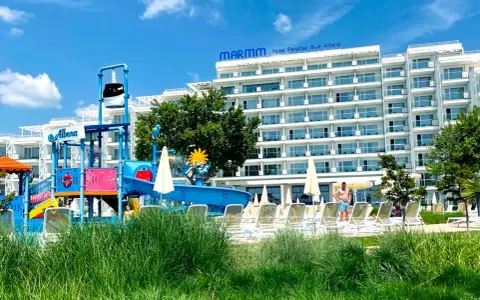 Kolorowy aquapark i hotel Maritim Paradise Blue Albena w Bułgarii, z leżakami i zieloną trawą.