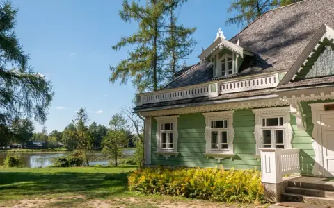 Zielony, drewniany dom z werandą i ozdobnymi detalami, nad jeziorem. Idealne miejsce na białowieża plan zwiedzania.