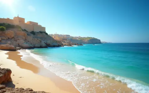 Piękna plaża z turkusową wodą i klifami, na których widać zabudowania. Czy to Cypr czy Malta?