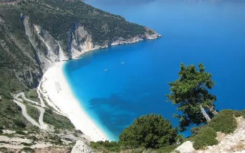 Malownicza plaża Myrtos na Kefalonii, Grecja w październiku. Kręta droga prowadzi do białego piasku i turkusowego morza.