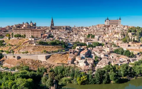 Widok na historyczne miasto Toledo w Hiszpanii, z katedrą i Alcázarem górującymi nad zabudowaniami.