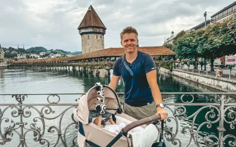 Szczęśliwy ojciec z niemowlakiem w wózku na moście, idealne miejsce, gdzie na wakacje z niemowlakiem.