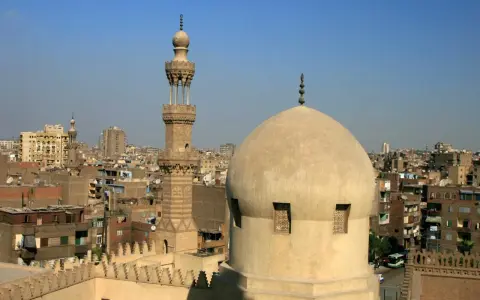 Widok na kopułę i minaret meczetu w Kairze, stolicy Egiptu, na tle miejskiego krajobrazu.