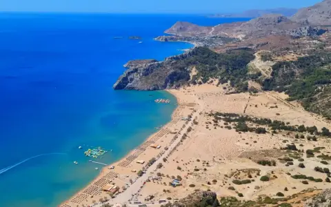 Malownicze plaże Rodos z turkusową wodą, piaszczystym wybrzeżem, leżakami i wodnym parkiem rozrywki.