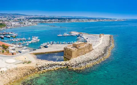 Pafos pogoda: Słoneczny dzień nad portem z zamkiem, jachtami i miastem w tle. Idealna pogoda na zwiedzanie Cypru.