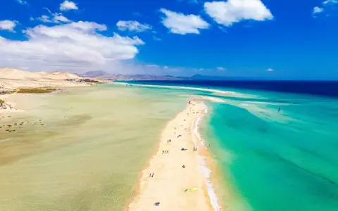 Plaża na Fuerteventurze, z turkusową wodą i piaszczystym cyplem, zachęca do wypoczynku. Czy to Fuerteventura czy Teneryfa, widok zapiera dech.