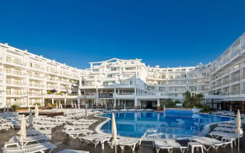 Idealna pogoda na Costa Brava: hotel z basenem i leżakami pod błękitnym niebem.