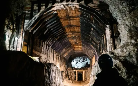 W ciemnym tunelu kopalni, gdzie drewniane wsporniki tworzą łuk, widać sylwetkę górnika. Czy to osówka, czy włodarz?