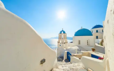 Santorini, październik. Słoneczna pogoda, białe domy i niebieskie kopuły kościołów nad Morzem Egejskim.